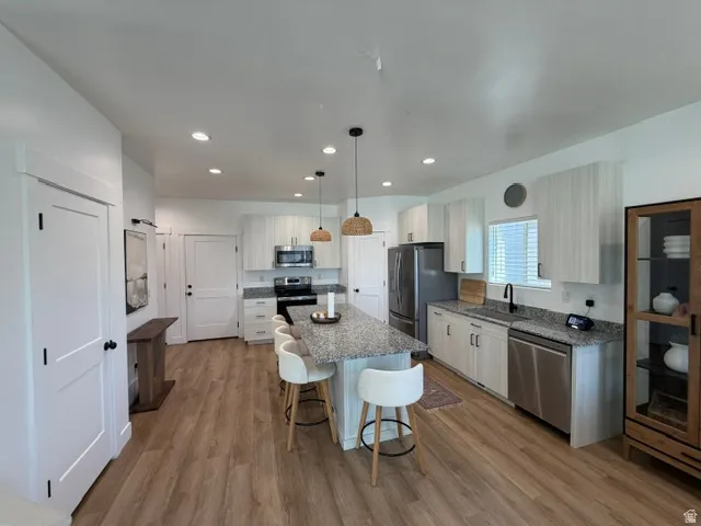 Kitchen featuring wood-finish flooring, granite countertops, and stainless steel appliances