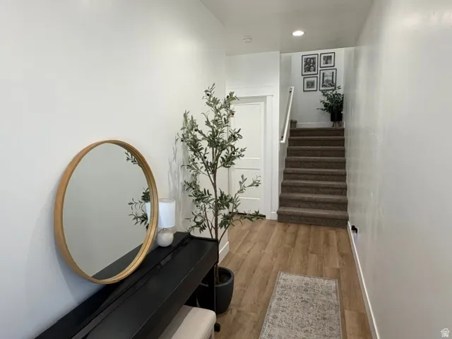 Hardwood-finish flooring, recessed lighting, white walls, and a carpeted staircase with white railing