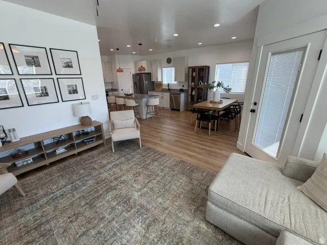 Open-concept living space featuring wood-finish flooring, recessed lighting, and a white interior door with integrated blinds