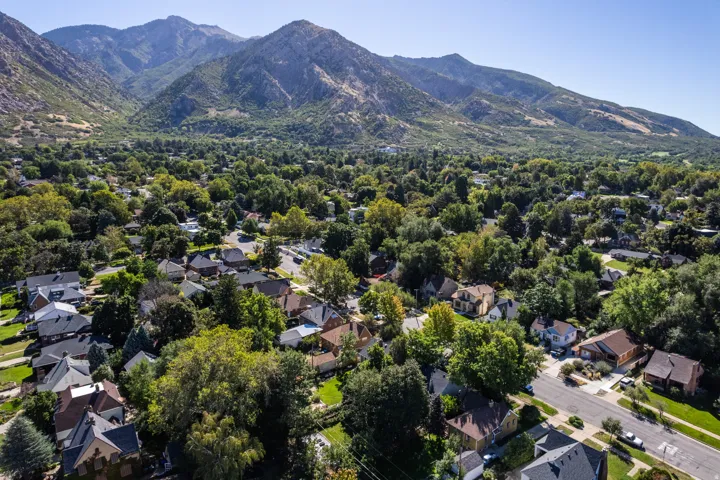 Residential neighborhood with mature trees, established properties, paved streets, and mountainous terrain