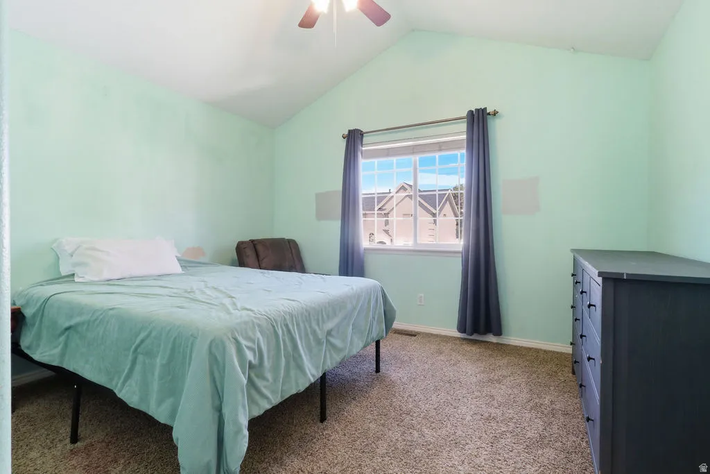 Vaulted ceiling, ceiling fan, window with curtain rod, neutral carpet, light green walls