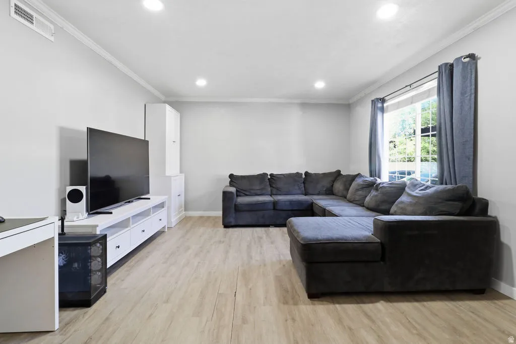 Light wood-finish flooring, recessed lighting, and crown molding