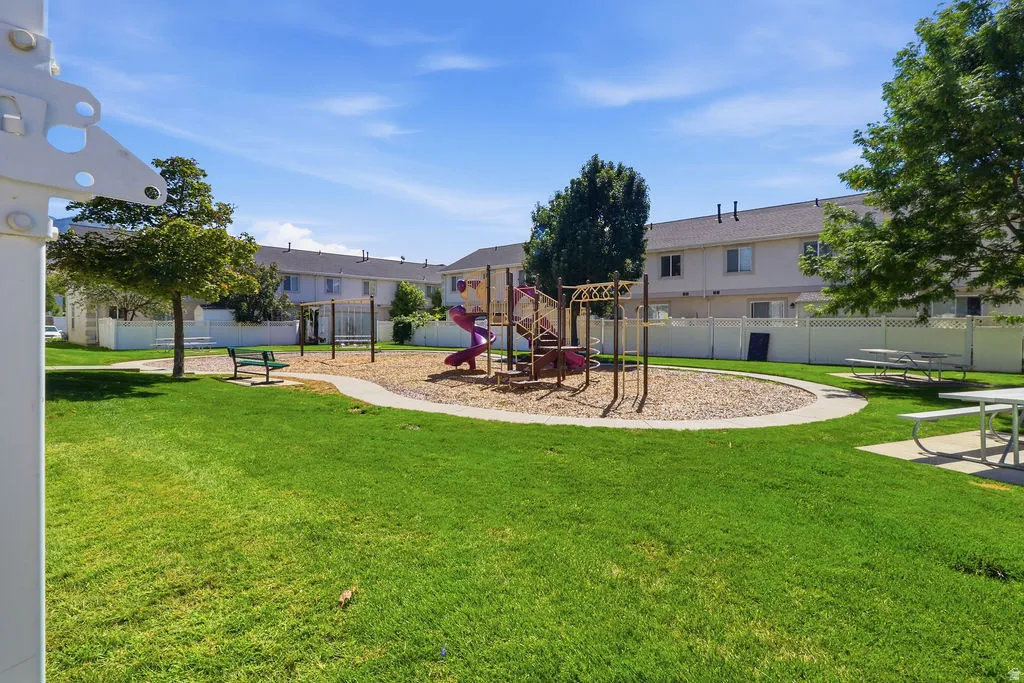 Community green space featuring a playground, picnic tables, and mature trees