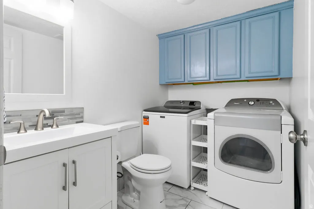 White vanity with integrated sink, brushed nickel faucet, and a tiled backsplash