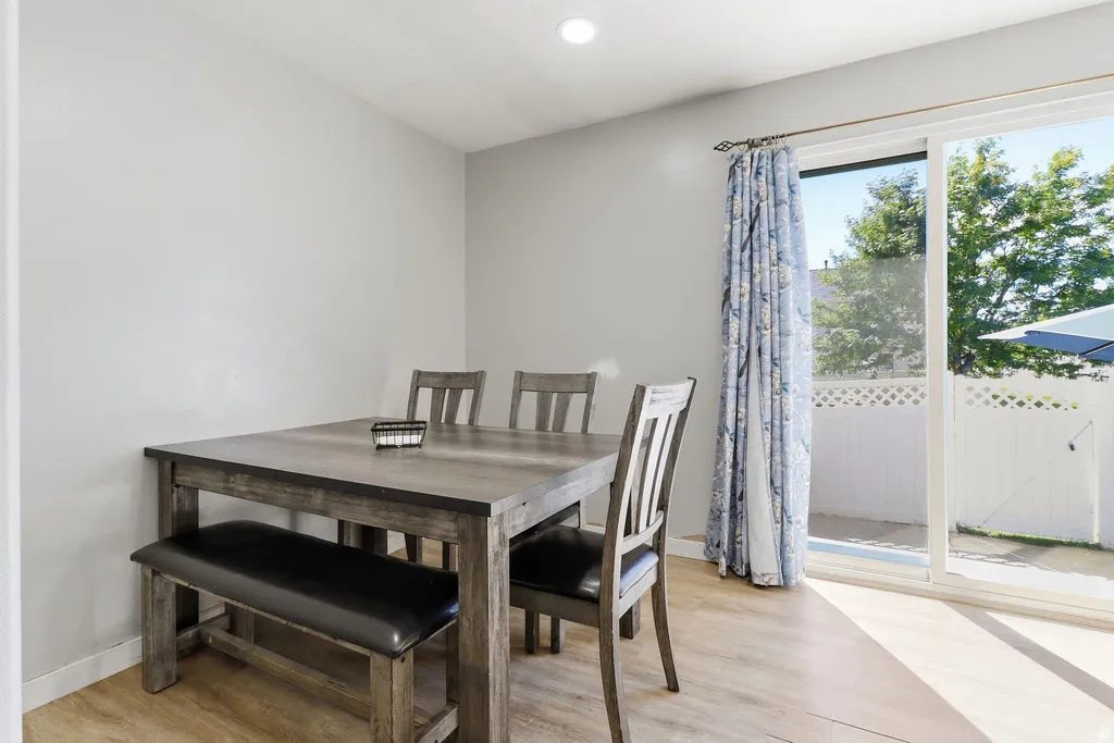 Sliding glass door, wood-finish flooring, recessed lighting, privacy fencing, and a paved outdoor area