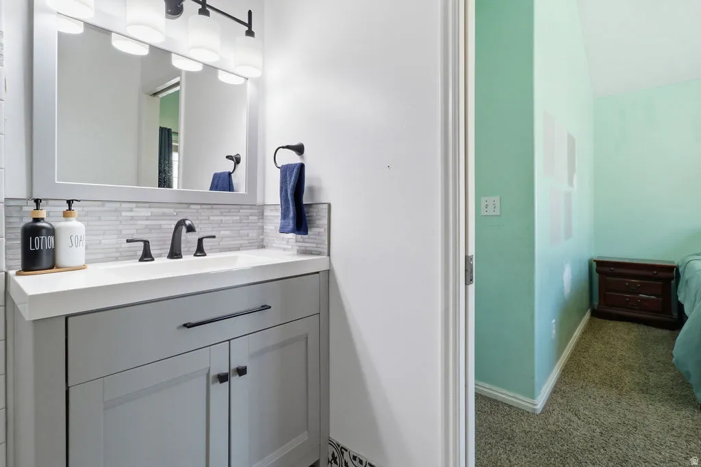 Vanity with an integrated sink, matte black faucet, and a tiled backsplash