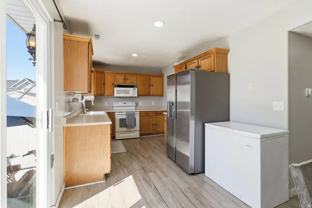 Kitchen with wood-finish cabinetry, white countertops, and stainless steel refrigerator
