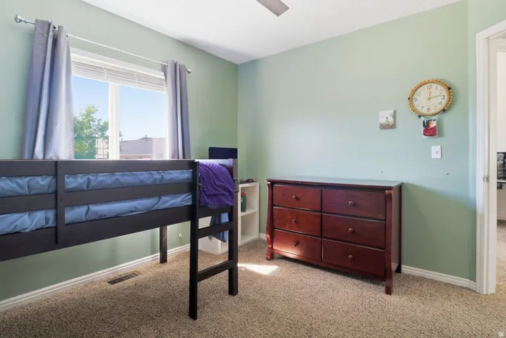 Carpeted room with a ceiling fan, a window with blinds, and a built-in shelf