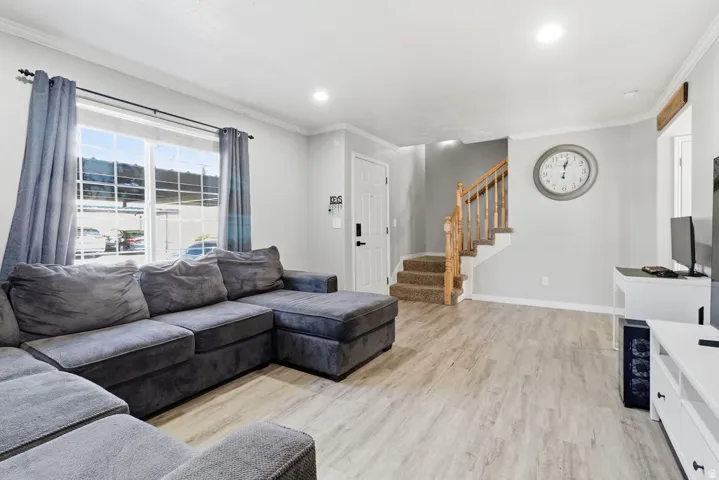 Light-colored wood-finish flooring throughout, bright window with white trim, and a staircase featuring wood railings