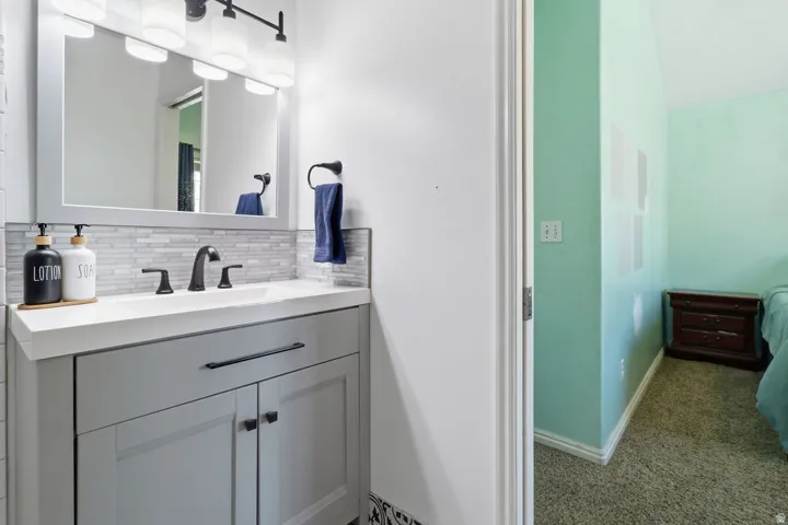 Vanity with an integrated sink, matte black faucet, and a tiled backsplash