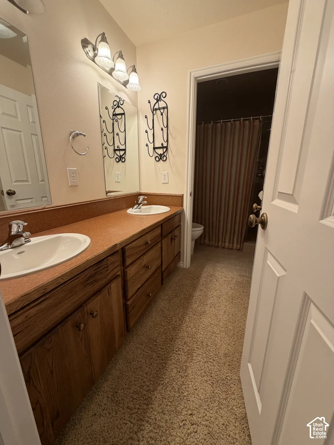 Dual vanity with integrated sinks, wood-finish cabinetry, and overhead lighting