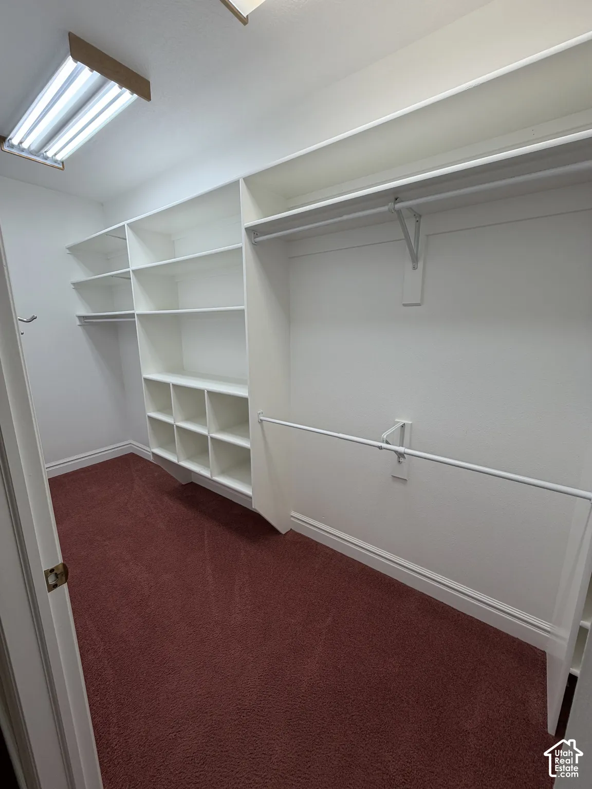 Built-in shelving, multiple hanging rods, and an overhead fluorescent light fixture