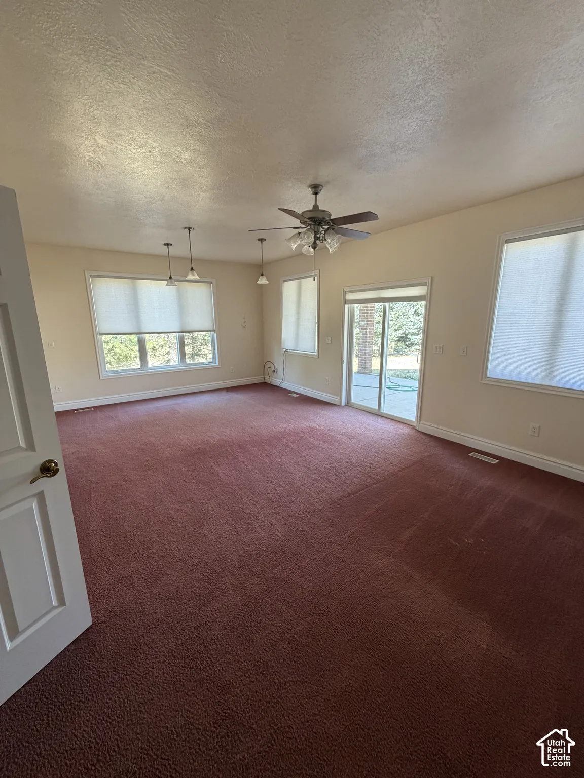 Spacious room with multiple windows, a ceiling fan, and pendant lighting