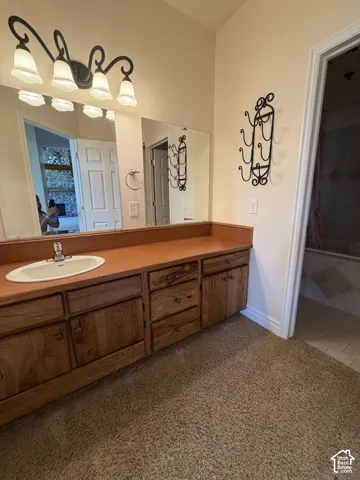 Vanity with single basin sink, wood-finish cabinetry, and a full-width mirror