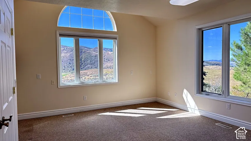 Room featuring vaulted ceilings, an arched window, large multi-pane windows, and mountain scenery