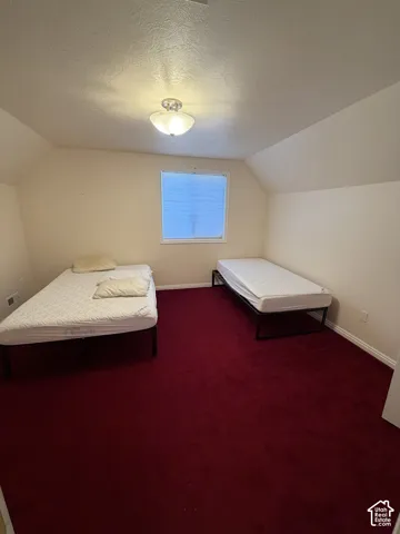Room featuring a window with blinds, a ceiling-mounted light fixture, sloped ceiling details, and red carpeting
