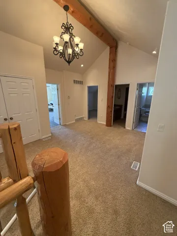Vaulted ceiling with exposed wood beams, wrought iron chandelier, recessed lighting, and neutral carpeting