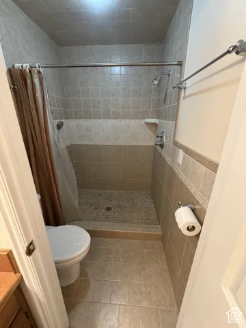 Shower with full-height tile surround, mosaic shower floor, and a built-in shower caddy