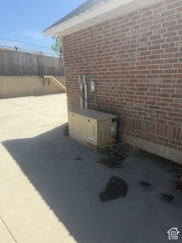 Brick exterior with a metal roof overhang, featuring a concrete pad and utility boxes