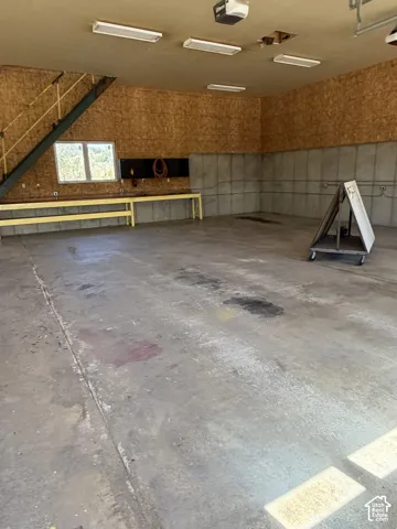 Concrete flooring with built-in workbench, wall-mounted electrical outlets, and overhead fluorescent lighting fixtures