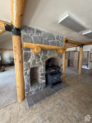 Stone fireplace with a brick firebox and a substantial wood mantel, featuring a wood-burning stove on a stone hearth