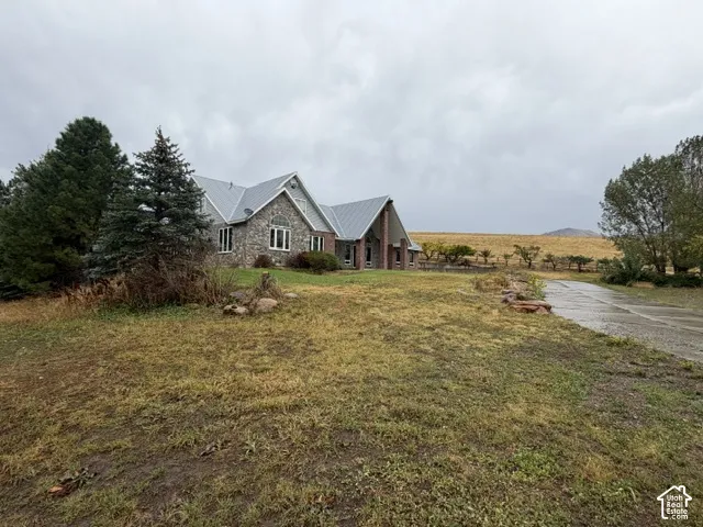 Stone facade residence with a metal roof, featuring multiple gables and a paved driveway