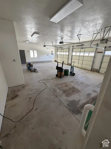 Three overhead fluorescent light fixtures, three garage doors with windows, and a concrete floor
