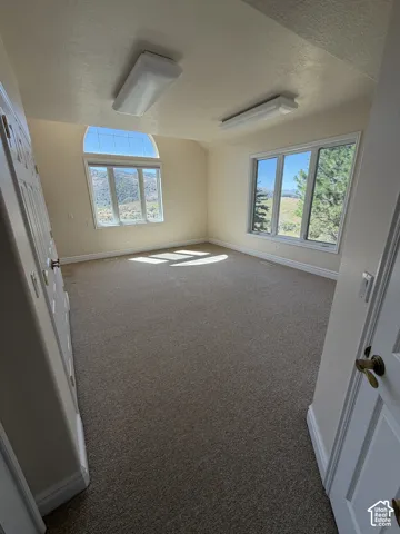 Carpeted room with a large arched window and a multi-pane window
