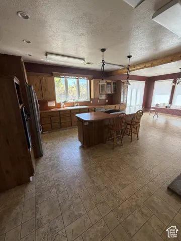 Spacious kitchen featuring extensive wood cabinetry, an oversized central island with seating, tile flooring, and recessed lighting