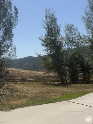 Concrete paving, split-rail fencing, and mature trees define the property's edge