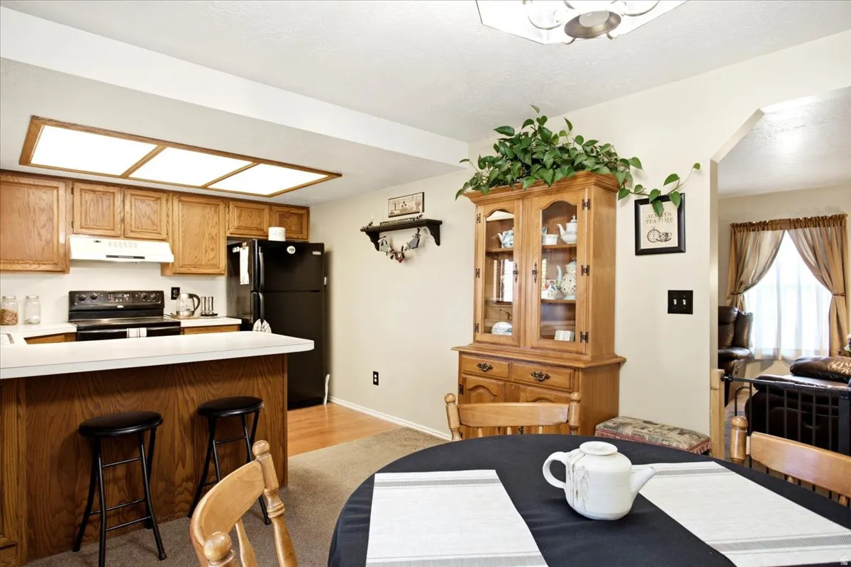 Kitchen featuring wood cabinetry, white countertops, and black appliances