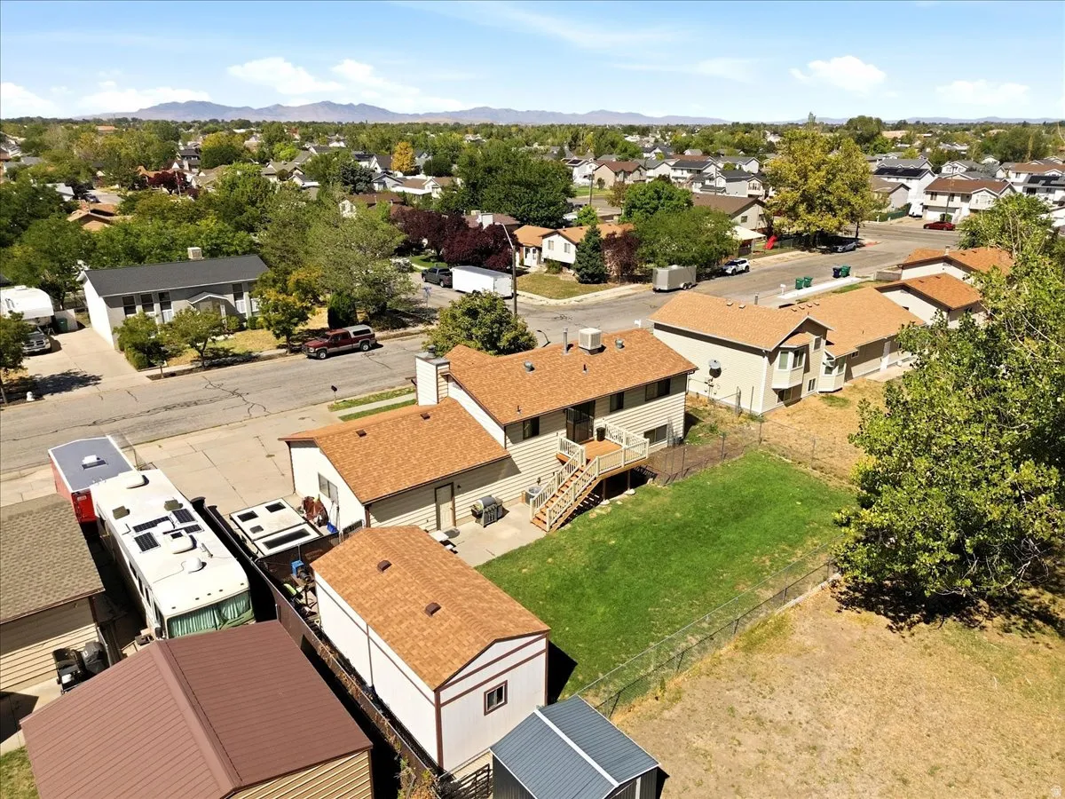 Expansive lot featuring a green lawn, mature trees, and storage shed