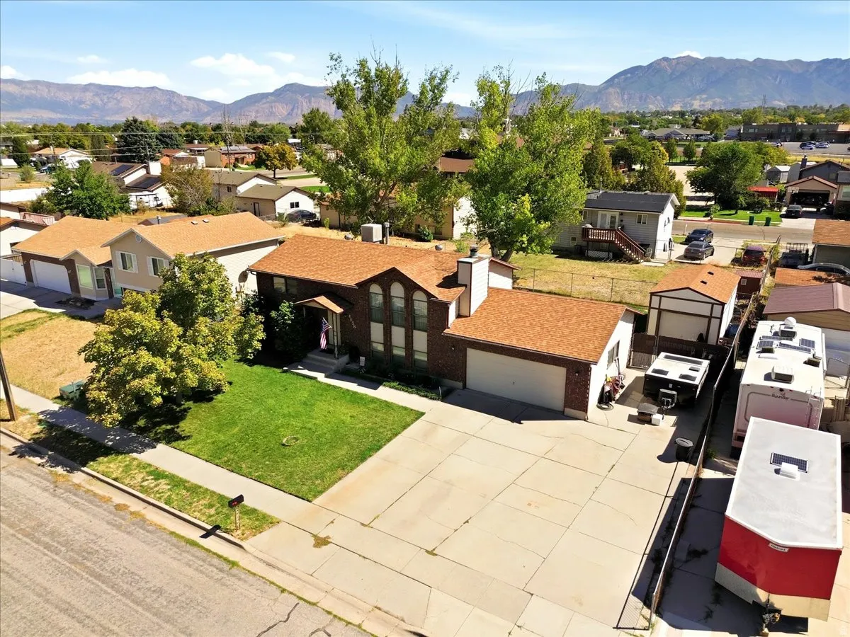 Brick exterior with an attached garage, paved driveway, and a front lawn