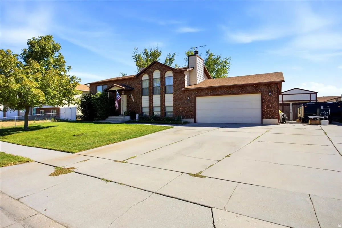 Brick exterior with arched windows, attached garage, covered entryway, and concrete driveway