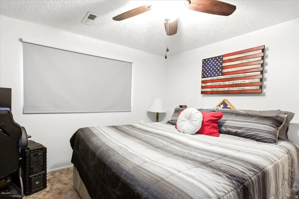 Recessed lighting, ceiling fan with wood-finish blades, and window with roller shade