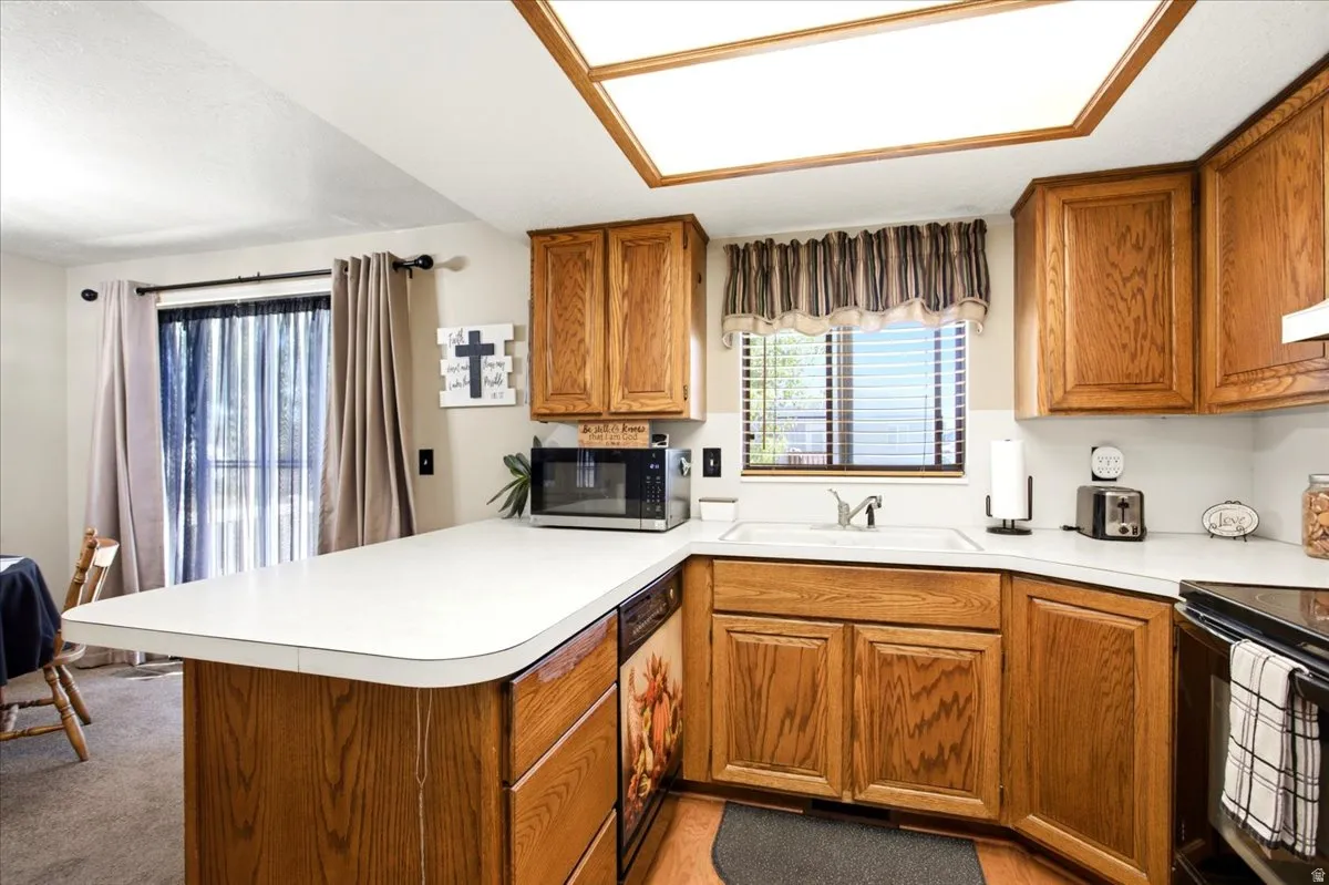 Kitchen featuring wood cabinetry, white countertops, a stainless steel sink, and wood-finish flooring