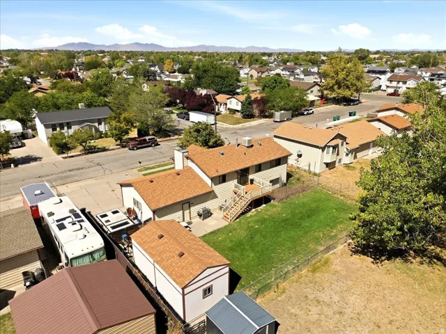 Expansive lot featuring a green lawn, mature trees, and storage shed
