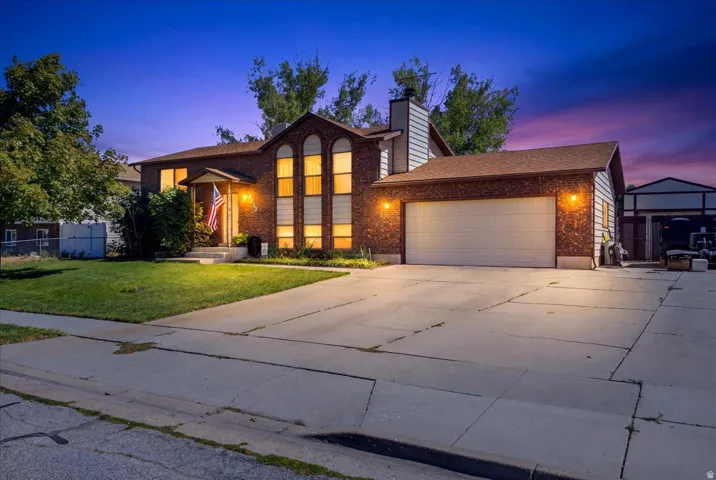 Brick exterior with a prominent front entrance, large arched windows, attached garage, and a concrete driveway