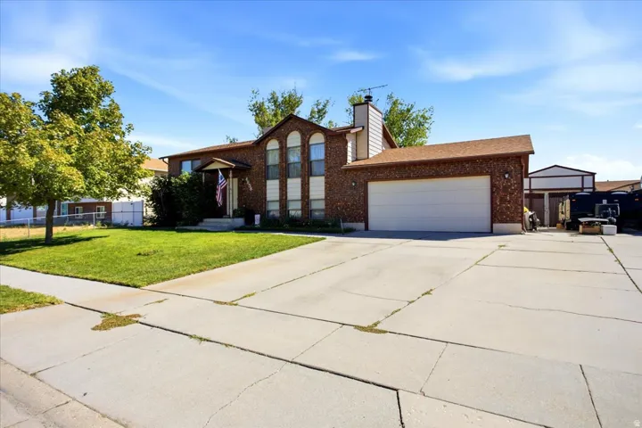 Brick exterior with arched windows, attached garage, covered entryway, and concrete driveway