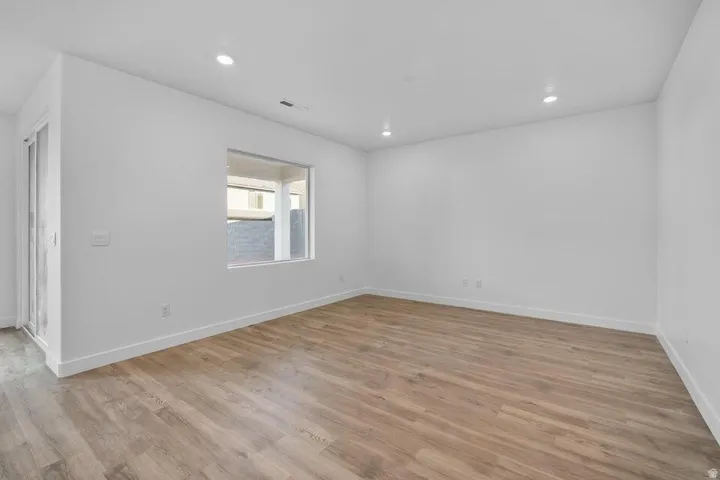 Recessed lighting throughout, wood-finish flooring, and a large window