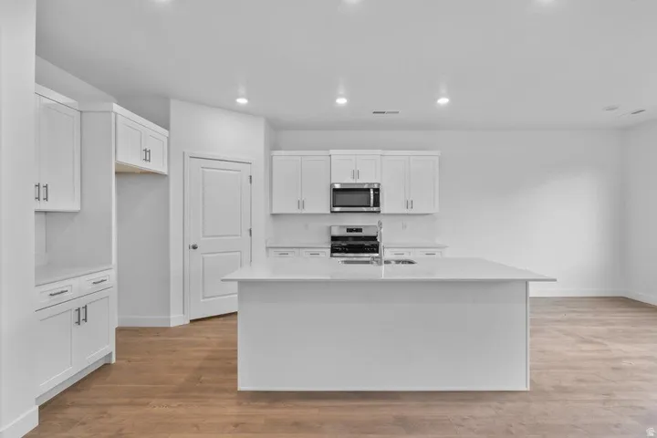 Modern kitchen featuring an expansive center island, white cabinetry, integrated stainless steel appliances, and recessed lighting
