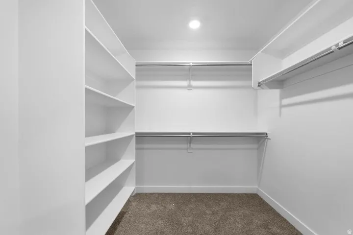 Built-in shelving, multiple hanging rods, recessed lighting, and carpet flooring