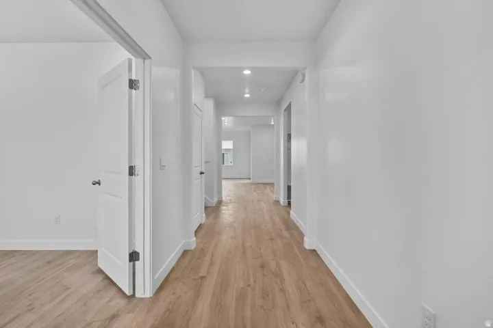 Hallway featuring wood-finish flooring, white walls, and recessed lighting