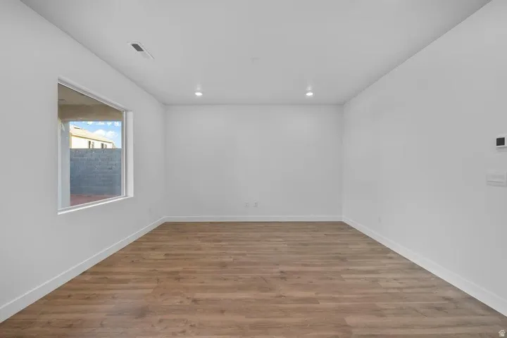 Recessed lighting, wood-finish flooring, and white walls