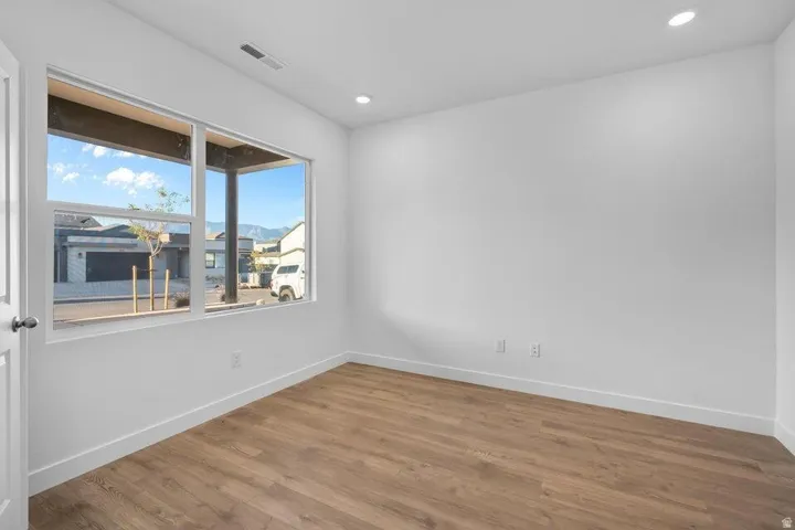Recessed ceiling lighting, white painted walls, wood-finish flooring, and a large window