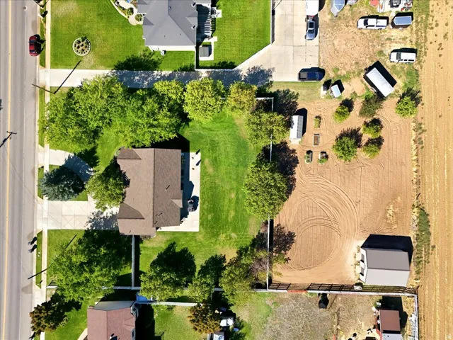 Expansive parcel featuring a main residence with a brown shingle roof, mature landscaping, and a substantial unpaved area