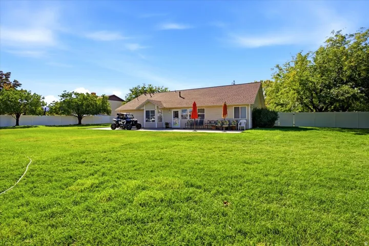 Expansive green lawn, durable vinyl fencing, mature trees, and a spacious rear patio