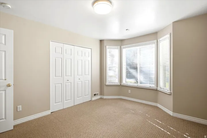 Recessed lighting, bay windows with blinds, carpeted flooring, and bi-fold closet doors