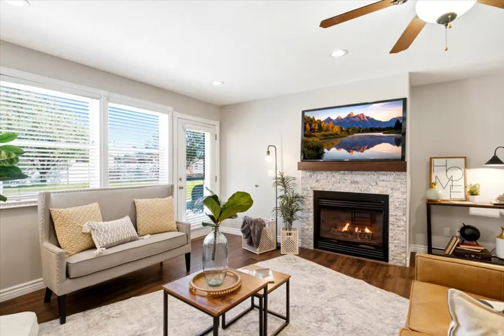 Living area featuring a natural gas fireplace with stone surround, a wood mantel, and wood-finish flooring