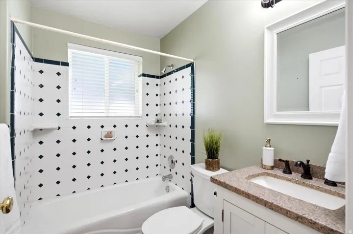 Bathroom featuring a white vanity with a built-in sink, stone-finish countertop, and a framed mirror